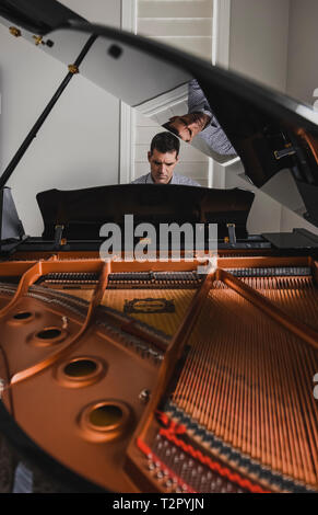 Mann spielt Baby Grand Piano mit der Innenseite des Piano im Vordergrund Stockfoto