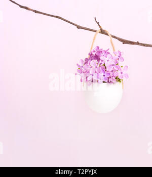 Blumen Flieder (Syringa) in Eierschale auf rosa Hintergrund. Ostern Dekor. Stockfoto