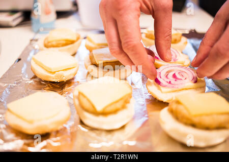 Person ist die Vorbereitung mini Chicken Burger, indem sie rote Zwiebel auf Fleisch Stockfoto