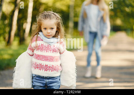 Junge blonde Mutter hinter ihr super energetische toddler Tochter in einem sonnigen Park Stockfoto