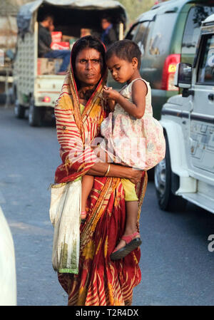 Bettler Frau mit ihrem Kind zwischen Autos auf einer Straße in Guwahati, Assam, Indien --- Bettlerin mit ihrem Art zwischen Autos auf einer Straße in Guwahati, Bundesstaat Assam, Indien Stockfoto