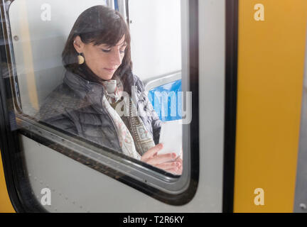 Casual Wear Frau mit einem Smartphone, während im Zug sitzen Stockfoto