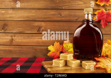 Ahorn Sirup Flasche auf einem Holzbrett. Ahornblätter in der Dekoration. Kopieren Sie Platz für Ihren Text. Stockfoto