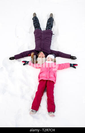 Mutter und Tochter machen Schnee Engel Stockfoto