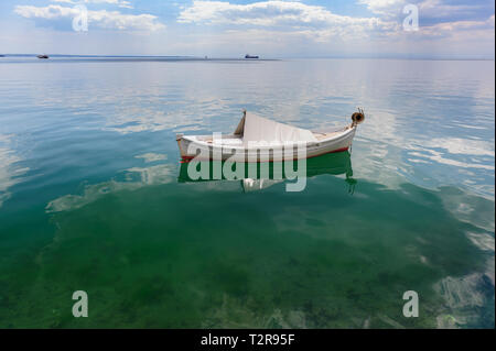 Sehr kleine weiße Fischerboot in Thessaloniki an der Meeresoberfläche, antike griechische Amphore Unterwasser im linken unteren Teil Stockfoto