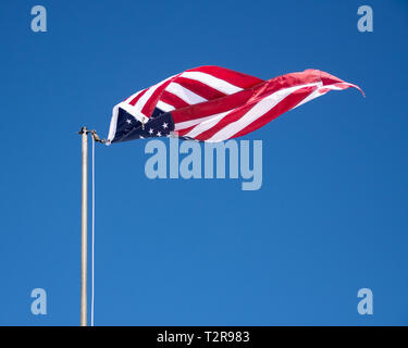 Eine amerikanische Flagge ausgehängt aus der Linie Verdrehen im Wind gegen einen klaren blauen Himmel. Stockfoto