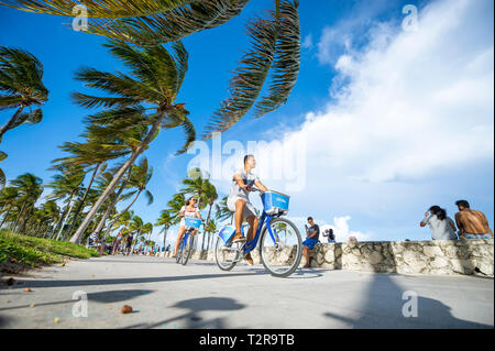 MIAMI - September 2018: ein paar junge Touristen pass Citibikes, eine Marke, genießt eine exklusive Bike-sharing-Vereinbarung mit Miami Beach. Stockfoto