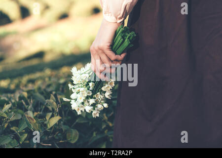 Nahaufnahme der weiblichen Hand ein Bündel von schneeglöckchen im Hintergrund der Landschaft Stockfoto