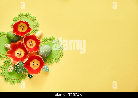 Ostern flach auf gelbem Papier Hintergrund. Anordnung von Tulip Blumen und Ostereier, copy-Platz auf der Seite. Stockfoto