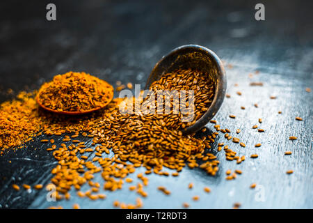 Nahaufnahme von ayurvedische Kraut Alsi oder Adsi oder Leinsamen in einer schwarz gefärbten Ton Schüssel mit dem Pulver auf Holz- Oberfläche in einem Viele ayurvedische Medizin verwendet Stockfoto