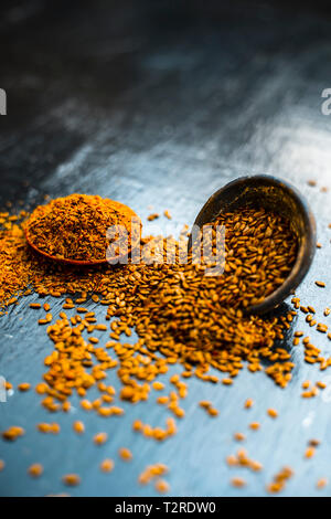 Nahaufnahme von ayurvedische Kraut Alsi oder Adsi oder Leinsamen in einer schwarz gefärbten Ton Schüssel mit dem Pulver auf Holz- Oberfläche in einem Viele ayurvedische Medizin verwendet Stockfoto