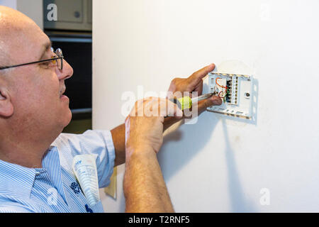 Miami Beach Florida, Presidential Wohnanlagen, Klimaanlage Mechaniker, hispanische Männer männlich, Arbeiter, Arbeiter, Techniker, digitaler Thermostat, installieren, inst Stockfoto