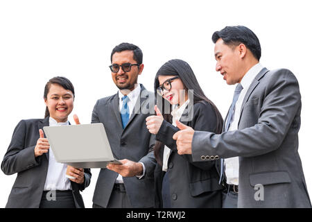 Zwei Geschäftsfrauen und zwei Geschäftsleute auf Notebook Computer und heben Daumen hoch, mit lächelnden Gesichtern auf weißem Hintergrund Stockfoto