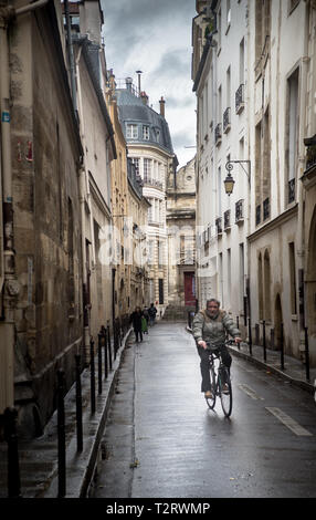 Man Radfahren entlang der Rue im Marais im Winter Stockfoto