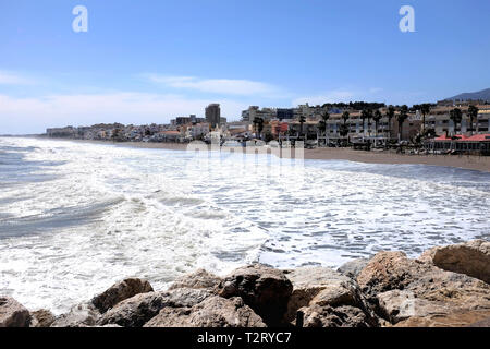 Torremolinos, Küste del Sol, Spanien. März 27, 2109. Urlauber zu Fuß die Strandpromenade auf der South Beach an einem windigen Tag im März in Spanien. Stockfoto