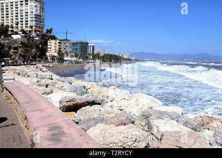 Torremolinos, Costa del Sol, Spanien. März 27, 2019. Touristen zu Fuß die Promenade und der Strand enjoyng an einem windigen Tag im März in Torremolinos. Stockfoto