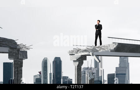 Zuversichtlich Geschäftsmann in Anzug weg schauen beim Stehen auf Broken Bridge mit Stadtbild auf Hintergrund. 3D-Rendering. Stockfoto