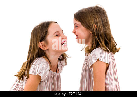 Zwilling Mädchen sind sich einander und lächelnd. Konzept der Familie und schwesterliche Liebe. Profil Seitenansicht des Twin sisters in den Kleidern suchen Stockfoto