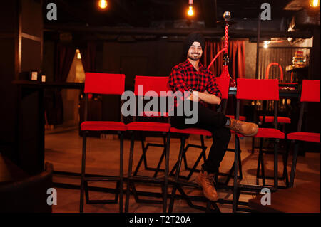 Inder in kariertem Hemd und schwarzen Turban an der Bar sitzen. Stockfoto