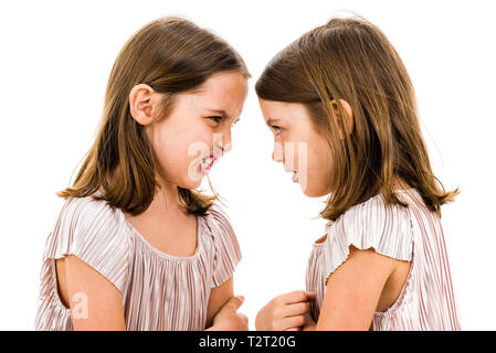 Identische Zwillinge Schwestern streiten sich gegenseitig zu beschimpfen. Böse Mädchen schreien, kreischen und argumentieren mit den emotionalen Ausdruck auf den Gesichtern. Fron Stockfoto