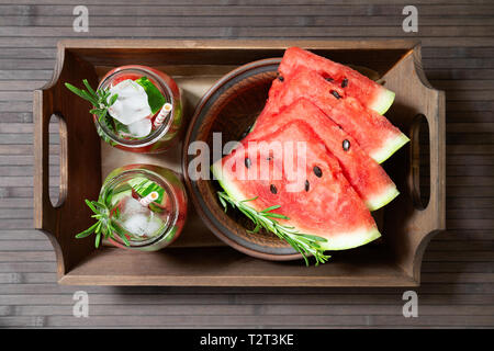 Zwei Gläser erfrischenden Sommer Wassermelonen trinken mit Rosmarin und Wassermelone auf einer hölzernen Fach Wassermelone und Rosmarin infundiert Wasser mit serviert. Stockfoto