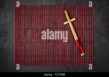 Japanische Tabelle einstellen. Bambus Stäbchen und Mat in Rot Schwarz Farben. Stockfoto