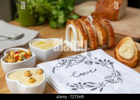 Herz geformte Schüsseln mit Hummus und Kichererbsen Salat mit Toast Stockfoto