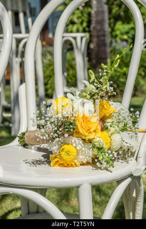 Farbenfrohe wedding bouquet mit gelben Rosen, Chrysanthemen und Sun Flowers Festlegung auf einem weißen Holzstuhl. Tropische Hochzeit. Stockfoto