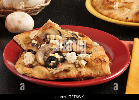 Naan Brot belegt mit schwarzen Oliven, sautierten Pilzen und Feta Käse Stockfoto