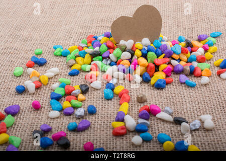 Herz aus Papier inmitten der bunten Steinchen auf Leinwand Boden Stockfoto