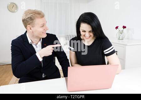 Vorgesetzten arbeitet mit unterordnen. Blonder mann Punkte Finger auf Schwarz behaarte Frau, emotional diskutieren Stockfoto