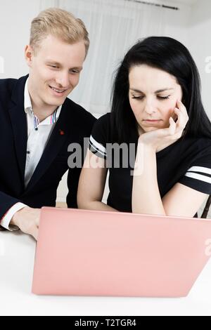 Vorgesetzten arbeitet mit unterordnen. Blonder Mann mit schwarzen Haaren Langeweile Frau Stockfoto
