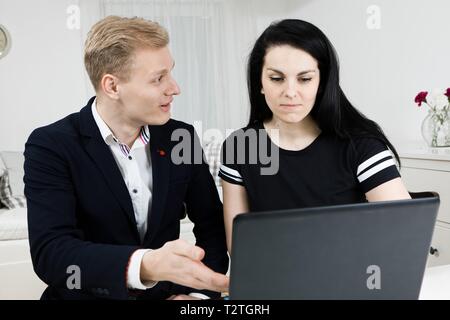 Vorgesetzten arbeitet mit unterordnen. Blonder Mann erklärt schwarzhaarige Frau, emotional diskutieren Stockfoto