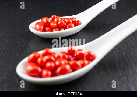 Frische Goji Beeren in kleinen weißen Porzellan Löffel auf dunkle Kopie Raum closeup isoliert Stockfoto