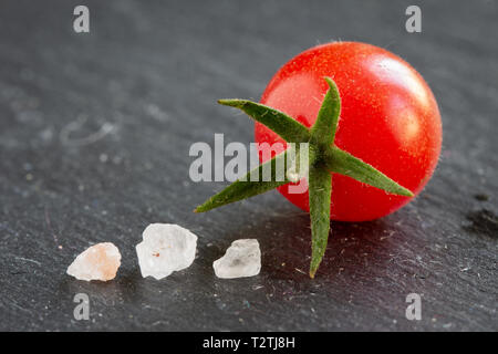 Frisches Wild Johannisbeere Tomaten closeup auf einer Schiefertafel Platte mit Kopie Raum und Salzkristalle isoliert Stockfoto