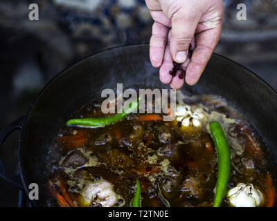 März 31, 2019 - Kiew, Ukraine - Rosinen, Berberitzen, Chili und Knoblauch Köpfe gesehen werden hinzugefügt Eintopf mit Karotten zu Lamm.. Pilav aus Lamm- oder Rindfleisch, Reis, Karotten und Zwiebeln mit Gewürzen, Beliebt ist es nicht nur unter den türkischen Völkern. In der Regel dieses Gericht ist in einem speziellen gusseisernen Topf namens Kessel vorbereitet und Sie sind in verschiedenen Größen von 8 Liter bis 1000 Liter. Wir haben die kleinsten Kessel. (Bild: © Igor Goiovniov/SOPA Bilder über ZUMA Draht) Stockfoto