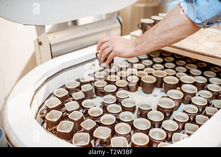 Mann unter Keramik Tassen aus dem Backofen an der Töpferei, Nahaufnahme Stockfoto