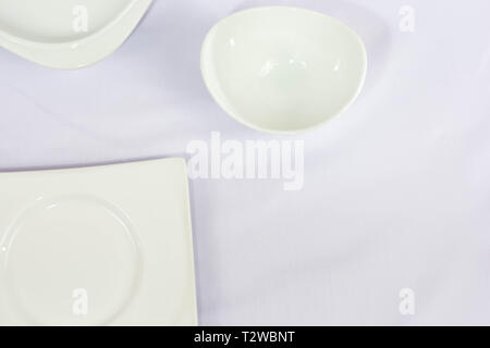 Flach der weissen Teller, Schüssel, weiß oder lila Stoff isoliert, einfachen minimalistischen Vorlage Konzept von oben Einsatzbereit - Bild Stockfoto