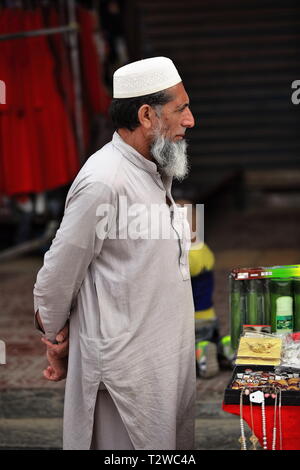 Doppa-tragend pakistanischer Verkäufer auf dem Sonntagsmarktstadt-Basar. Hotan-Xinjiang-China-0081 Stockfoto