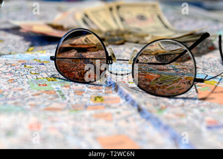 Sonnenbrille und Geld auf eine touristische Karte Hintergrund. Tourismus Konzept. Stockfoto