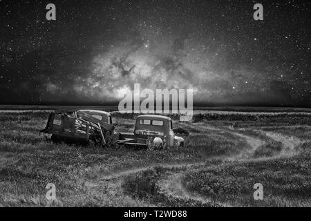 Zwei verlassene vintage Lkw neben einem Trail in einem Feld geparkt unter dem Himmel in einer ländlichen Landschaft Landschaft Stockfoto