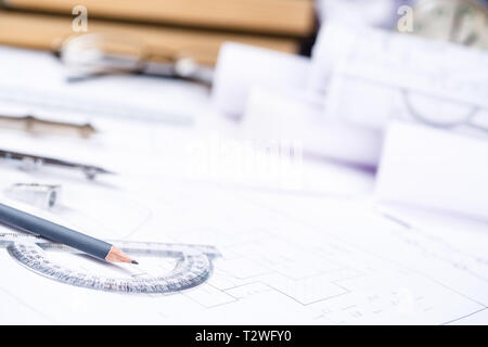 Bleistift mit einem winkelmesser vor dem Hintergrund der Schreibtisch des Ingenieurs. Architektonische Drucke und Walzen und einer Zeichnung Instrumente auf der worktabl Stockfoto