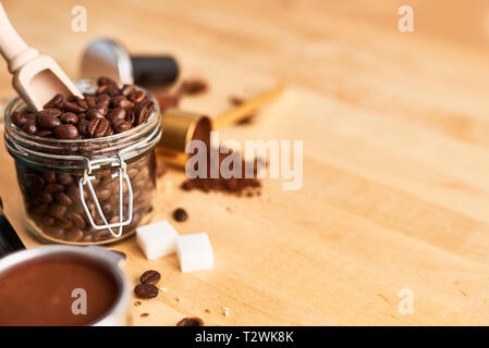 Frisch geröstete Kaffeebohnen in einem Glas, portafilter, gemahlenen Kaffee und auf Holz- Hintergrund. Kaffee Hintergrund. Kopieren Sie Platz für Text. Baris Stockfoto