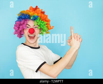 Junge lustig männliche Teenager im weißen T-Shirt auf blauem Hintergrund in clown Perücke Stockfoto