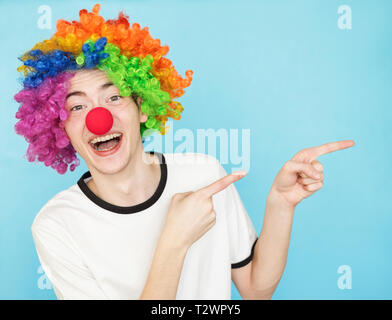 Junge lustig männliche Teenager im weißen T-Shirt auf blauem Hintergrund in clown Perücke copyspace Stockfoto