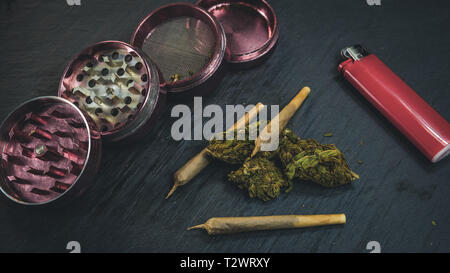 Marihuana Knospen und gemeinsame liegen auf einem dunkelgrauen Hintergrund. Grinder und leichter in der Nähe von Cannabis. Marihuana als Medizin. Stockfoto