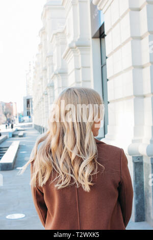 Elegante modische Frau mit Mantel mit lockigem Haar, street style Foto Stockfoto