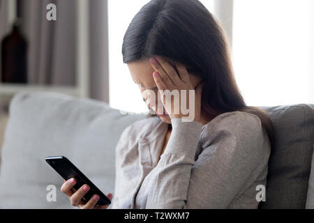 Verwirrt Frau sitzt auf der Couch empfangenen Nachricht fühlt sich enttäuscht Stockfoto