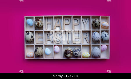 Ostern Eier. Frohe Ostern Text. Urlaub Dekoration rosa Hintergrund. Dekor Elemente in Holzkisten Stockfoto