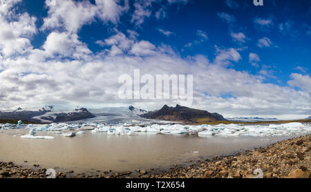 Panoramablick über schmelzende Eisberge in der Fjallsarlon Gletschersee mit Fjallsjokull Gletscher Kalben in Lagune im Hintergrund gesehen, Vatnajok Stockfoto